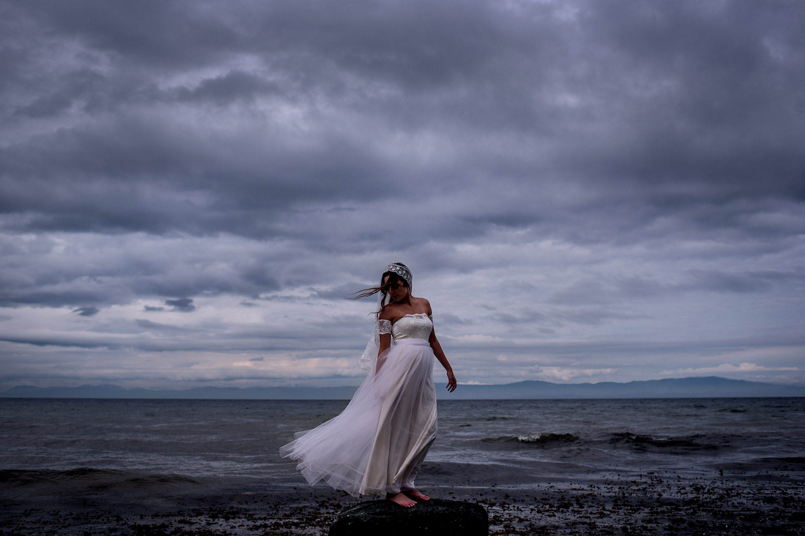 A beautiful bride standing on a rock for a portrait in BC - Qualicum Wedding Photographer