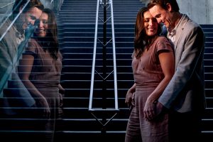 an engaged couple reflected in glass by calgary engagement photographer sean leblanc